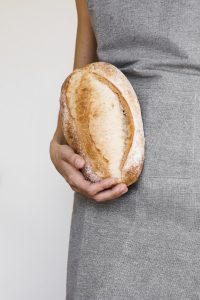 Person holding bread against their stomach which can be interpreted as an issue about digestion or intolerance